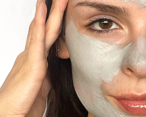 A close up of a woman's face. She's wearing a clay mask.